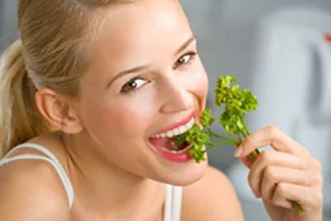 Young happy smiling woman eating at kitchen